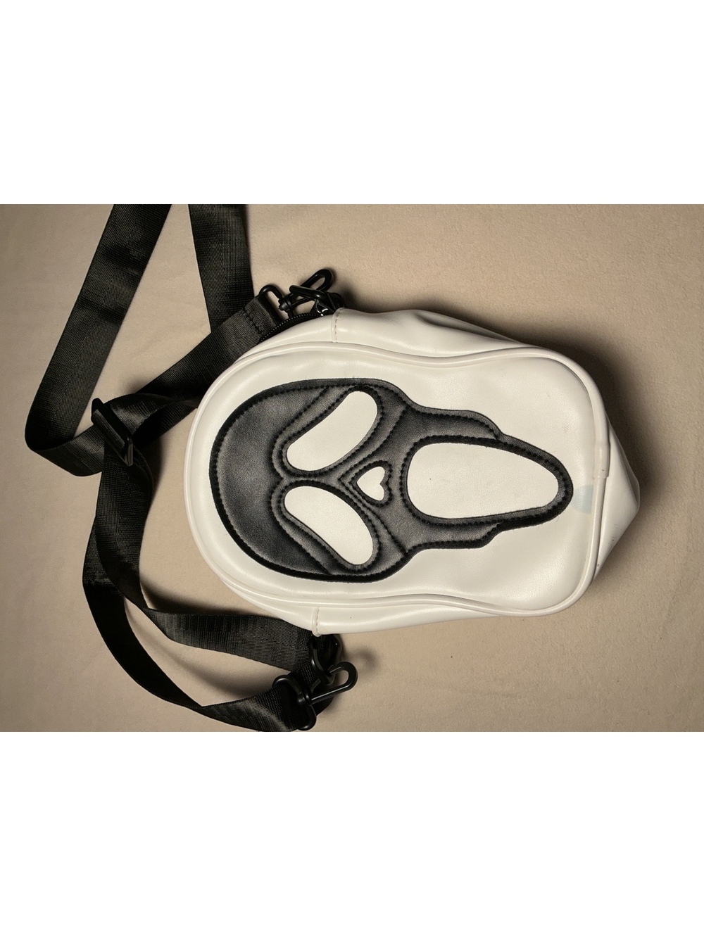 White mini backpack bag with black ghost face design